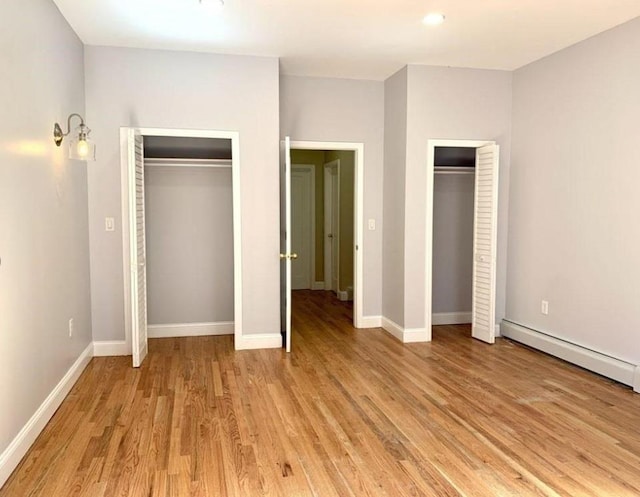 2301 Bathgate Ave, Bronx, NY 10458 - unfurnished bedroom featuring a baseboard radiator, multiple closets, and light wood finished floors