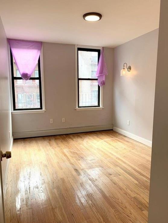 2301 Bathgate Ave, Bronx, NY 10458 - spare room with wood finished floors and a baseboard radiator