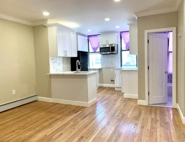 2301 Bathgate Ave, Bronx, NY 10458 - kitchen featuring stainless steel microwave, crown molding, freestanding refrigerator, tasteful backsplash, and white cabinetry