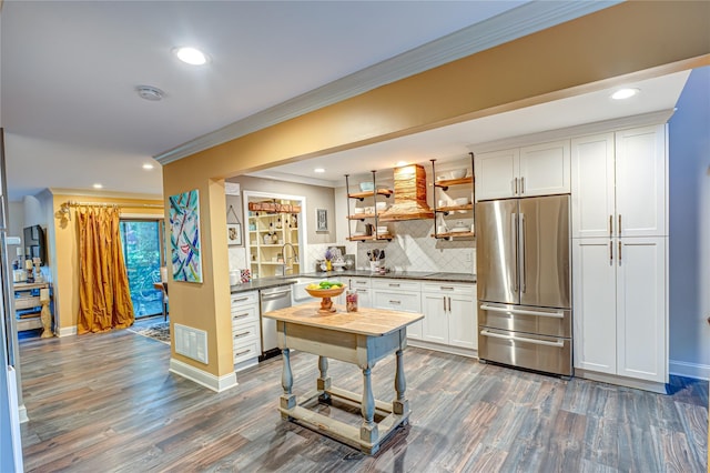 60 Jeremy Cir, Nesconset, NY 11767 - kitchen with appliances with stainless steel finishes, dark countertops, dark wood-style flooring, crown molding, and backsplash