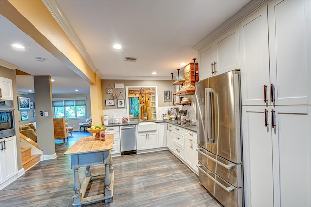 60 Jeremy Cir, Nesconset, NY 11767 - kitchen featuring stainless steel appliances, wood finished floors, ornamental molding, decorative backsplash, and dark countertops