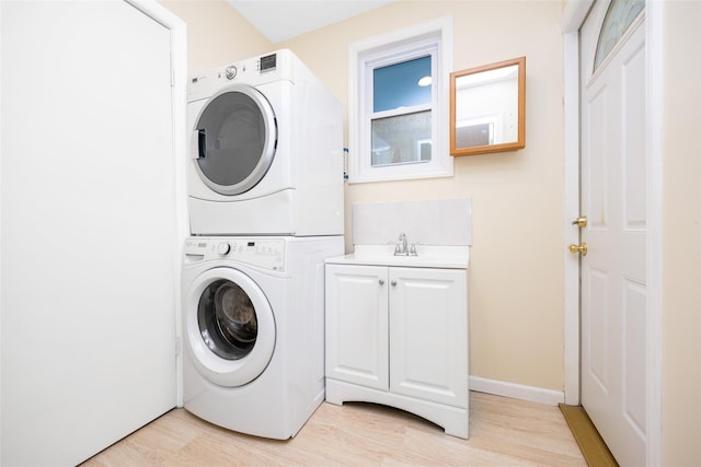 4 Wagon Ln, Levittown, NY 11756 - laundry area featuring stacked washer / drying machine, cabinet space, and light wood-type flooring