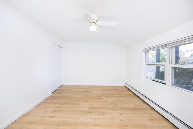 4 Wagon Ln, Levittown, NY 11756 - empty room with a baseboard heating unit, ceiling fan, vaulted ceiling, and light wood-style flooring