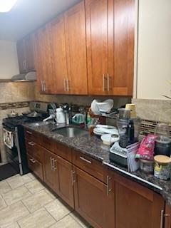 8602 89th St, Woodhaven, NY 11421 - kitchen with stainless steel range oven, brown cabinetry, and dark stone counters