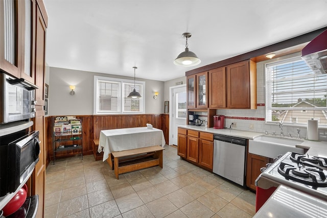 167 Hillview Ave, Yonkers, NY 10704 - kitchen featuring stainless steel appliances, brown cabinetry, a wainscoted wall, light countertops, and hanging light fixtures