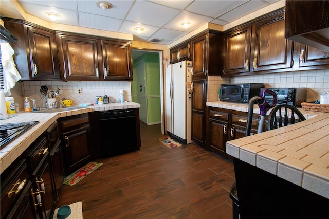 2083 Elm Pl, Merrick, NY 11566 - kitchen with tile countertops, black appliances, dark brown cabinets, decorative backsplash, and a paneled ceiling