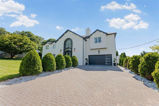 3 Fairview Ln, Glen Cove, NY 11542 - view of front of property featuring an attached garage, decorative driveway, a chimney, stucco siding, and a front lawn