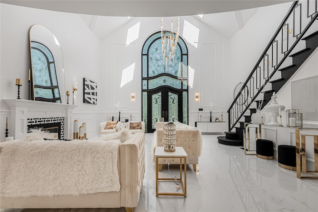 3 Fairview Ln, Glen Cove, NY 11542 - living area with high vaulted ceiling, a decorative wall, marble tiled flooring, stairs, and a chandelier