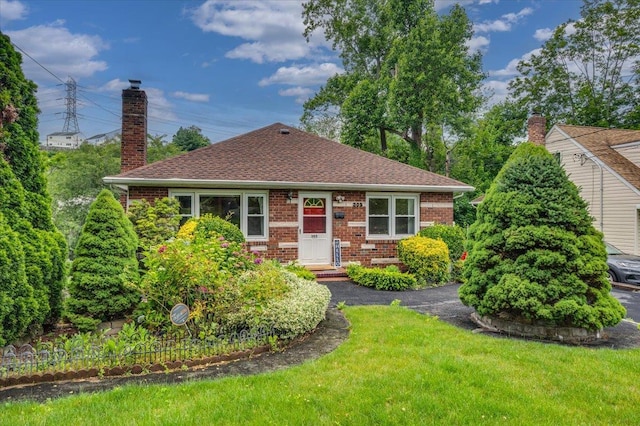 303 Helena Ave, Yonkers, NY 10710 - bungalow-style home featuring a chimney, brick siding, a front lawn, and a shingled roof