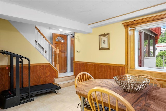 303 Helena Ave, Yonkers, NY 10710 - dining area featuring a wainscoted wall, wood walls, stairs, and light tile patterned flooring