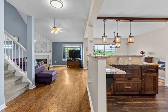 48 Sparrow Ridge Rd, Carmel, NY 10512 - kitchen with dark wood finished floors, a ceiling fan, a tiled fireplace, light stone counters, and a textured ceiling
