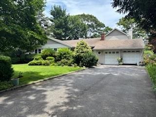 45 Mc Cue Ln, Babylon, NY 11702 - view of front of house with driveway, an attached garage, a front yard, and a chimney