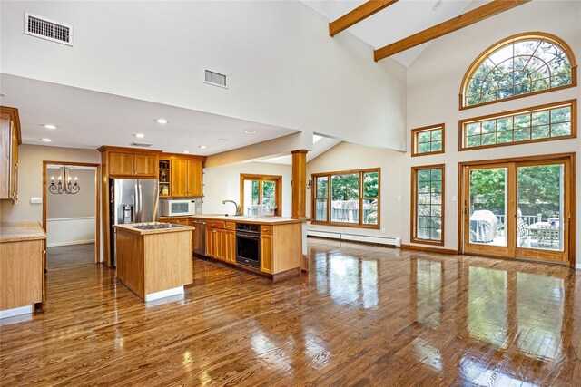 45 Mc Cue Ln, Babylon, NY 11702 - kitchen featuring appliances with stainless steel finishes, baseboard heating, dark wood finished floors, high vaulted ceiling, and a center island