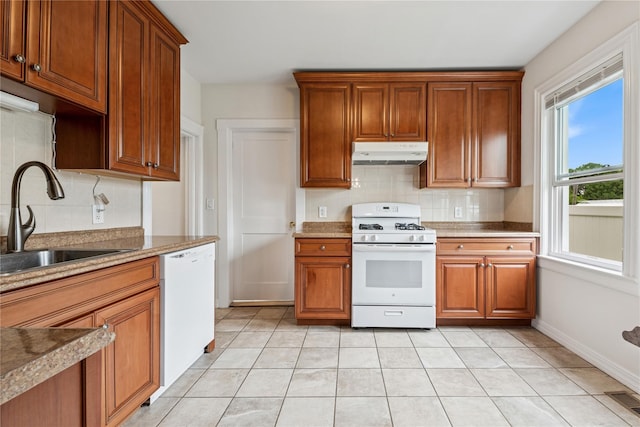 401 Ocean Ave, Malverne, NY 11565 - kitchen featuring white appliances, under cabinet range hood, backsplash, light tile patterned floors, and brown cabinetry