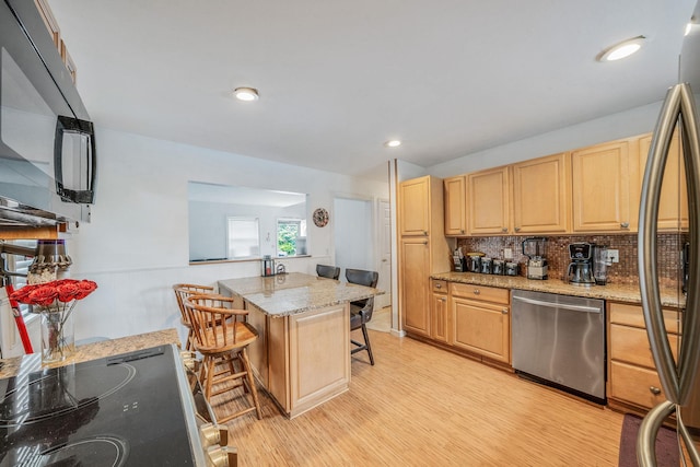 108A Union Ave, Lake Ronkonkoma, NY 11779 - kitchen with stainless steel appliances, light brown cabinetry, light wood-type flooring, a kitchen bar, and backsplash