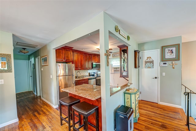 123 Lake St, Islip, NY 11751 - kitchen featuring appliances with stainless steel finishes, dark wood-style flooring, light stone countertops, ceiling fan, and a breakfast bar area