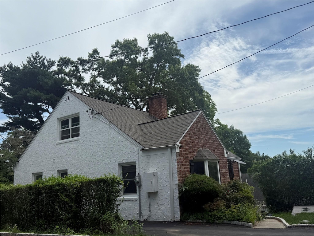 161 Harvard Dr, Hartsdale, NY 10530 - view of side of property with a chimney, roof with shingles, and stucco siding