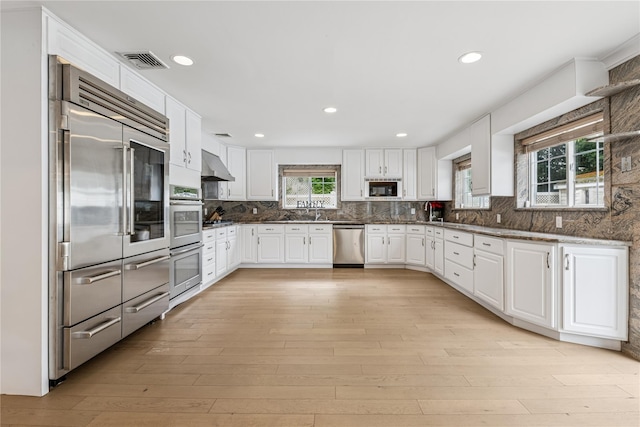 230 W Beech St, Long Beach, NY 11561 - kitchen featuring built in appliances, white cabinetry, light wood-style flooring, decorative backsplash, and recessed lighting