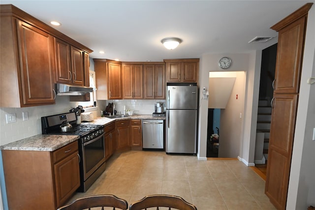 22 Victoria Rd, North Babylon, NY 11703 - kitchen featuring appliances with stainless steel finishes, decorative backsplash, light tile patterned floors, under cabinet range hood, and brown cabinetry