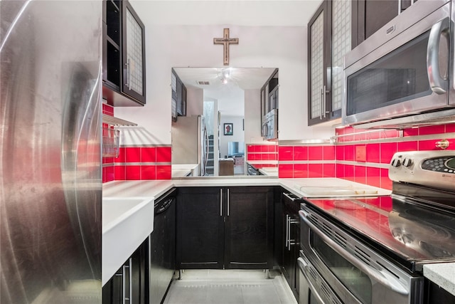 425 Shore Rd Unit 1A, Long Beach, NY 11561 - kitchen featuring appliances with stainless steel finishes, backsplash, light countertops, light tile patterned floors, and dark cabinetry
