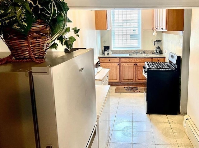 687 E 42nd St, Brooklyn, NY 11203 - kitchen featuring baseboard heating, range with gas stovetop, refrigerator, light countertops, and brown cabinetry