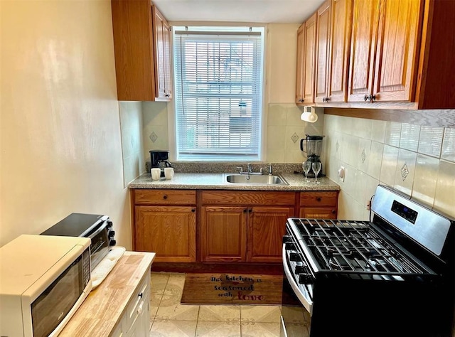 687 E 42nd St, Brooklyn, NY 11203 - kitchen with stainless steel gas range, tasteful backsplash, brown cabinets, and light tile patterned floors