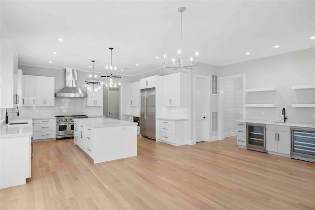 34 Old Main Rd, Quogue, NY 11959 - kitchen with wall chimney range hood, high end appliances, beverage cooler, a chandelier, and ornamental molding