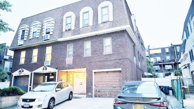 17-32 215th St, Bayside, NY 11360 - townhome / multi-family property with mansard roof, brick siding, an attached garage, and cooling unit