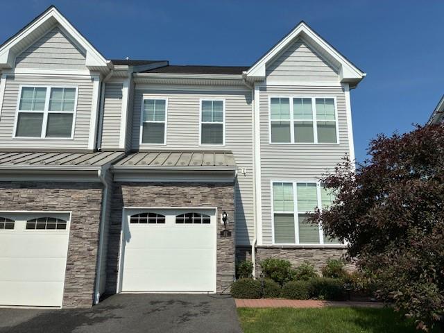 57 Lewis Rd, Hopewell Junction, NY 12533 - view of front of house with stone siding, a garage, a standing seam roof, driveway, and a metal roof