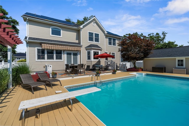 565 S 8th St, Lindenhurst, NY 11757 - rear view of house featuring a wooden deck, outdoor dining area, and an outdoor pool