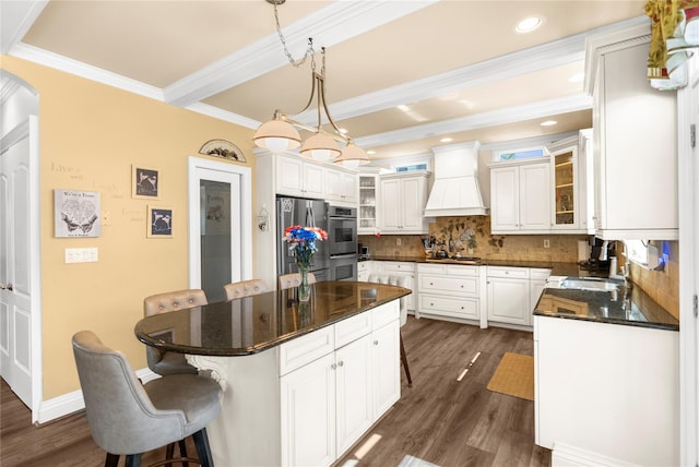 565 S 8th St, Lindenhurst, NY 11757 - kitchen featuring custom range hood, appliances with stainless steel finishes, dark wood-style flooring, backsplash, and a breakfast bar