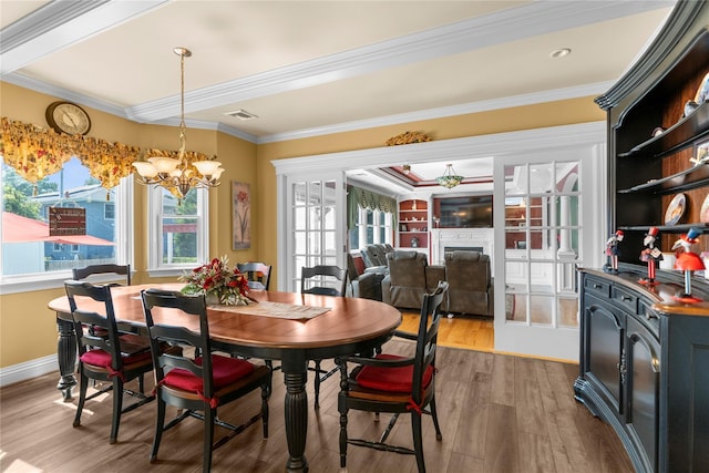 565 S 8th St, Lindenhurst, NY 11757 - dining space with wood finished floors, crown molding, a chandelier, and a fireplace