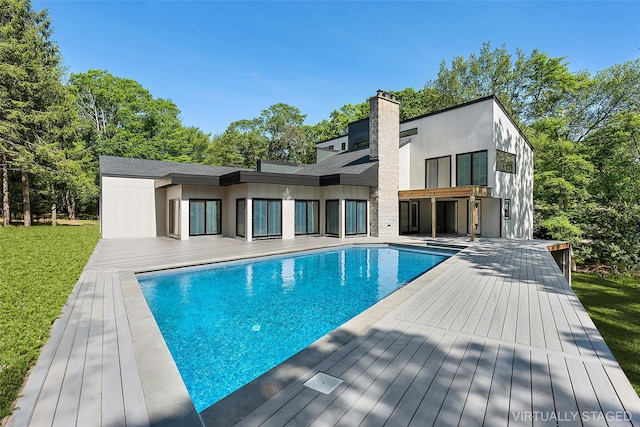 12 Plume Grass Way, Westhampton, NY 11977 - rear view of property featuring an outdoor pool, a chimney, a deck, and a lawn