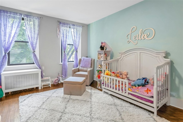 37 Central Ave Unit 2G, Hartsdale, NY 10530 - bedroom with radiator, a nursery area, and wood finished floors