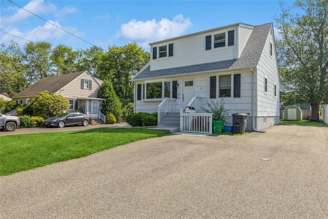 34 Klein Ave, West Nyack, NY 10994 - view of front of home with a storage shed, a shingled roof, a front yard, and asphalt driveway