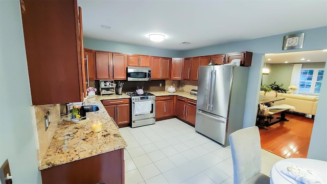 948 Orlando Ave, West Hempstead, NY 11552 - kitchen featuring stainless steel appliances, light stone countertops, backsplash, and brown cabinetry