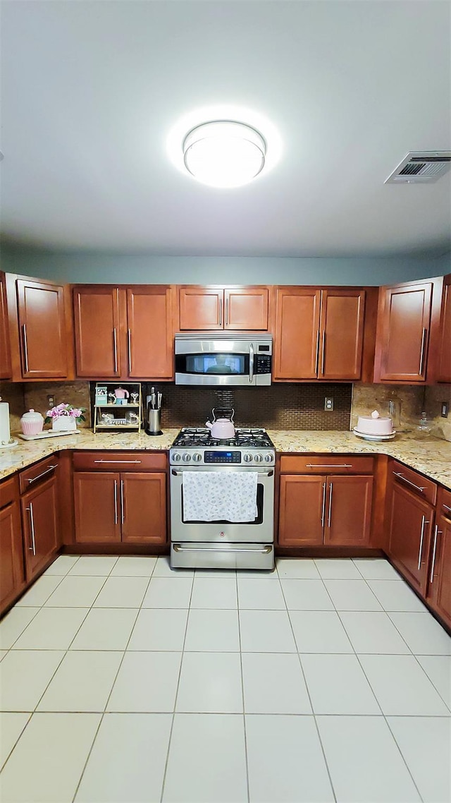 948 Orlando Ave, West Hempstead, NY 11552 - kitchen featuring stainless steel appliances, tasteful backsplash, light stone countertops, and light tile patterned flooring