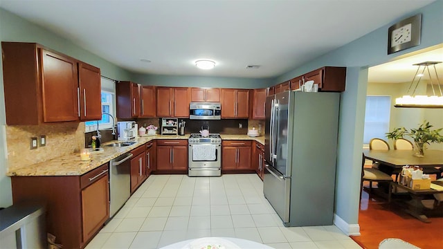 948 Orlando Ave, West Hempstead, NY 11552 - kitchen featuring stainless steel appliances, backsplash, light stone countertops, hanging light fixtures, and light tile patterned flooring