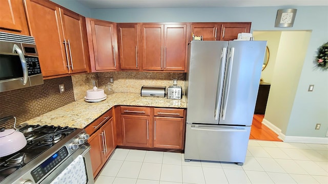 948 Orlando Ave, West Hempstead, NY 11552 - kitchen with stainless steel appliances, decorative backsplash, light stone countertops, and light tile patterned floors