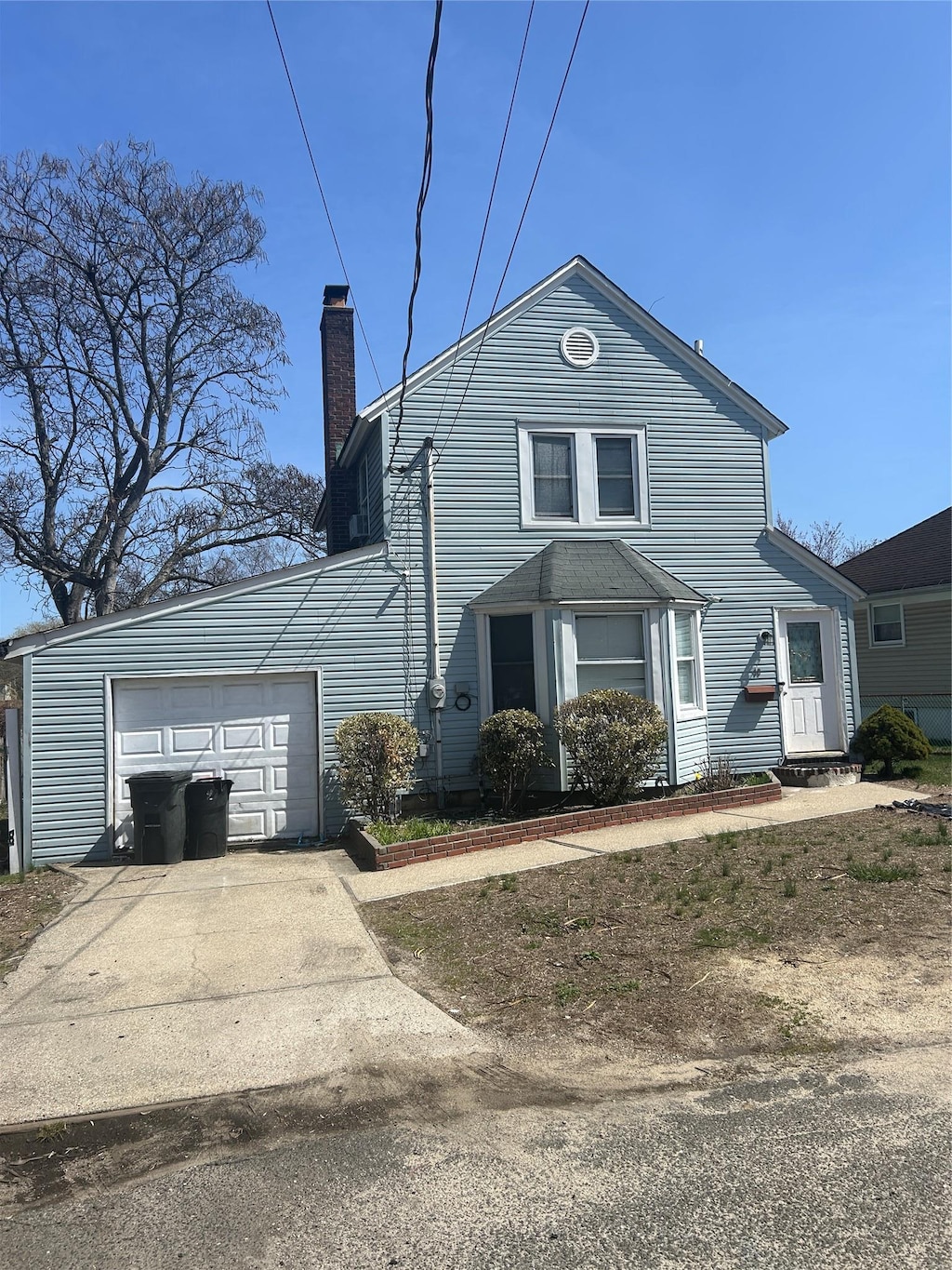 19 Westside Ave, Bay Shore, NY 11706 - view of front facade with concrete driveway, a chimney, and an attached garage