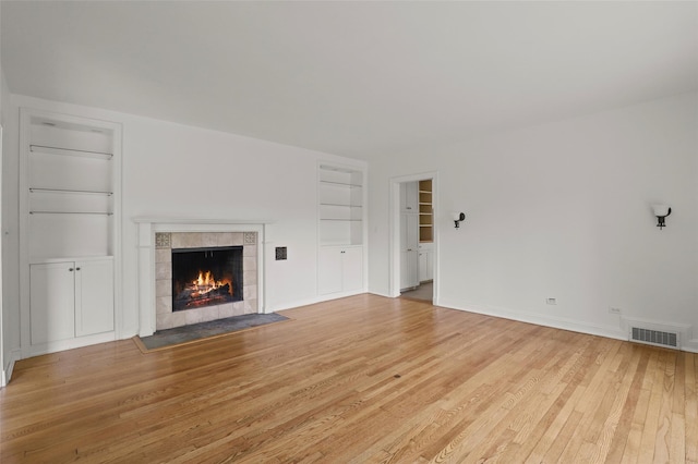 383 Pine Brook Rd, Bedford, NY 10506 - unfurnished living room featuring built in shelves, light wood-style floors, and a tiled fireplace