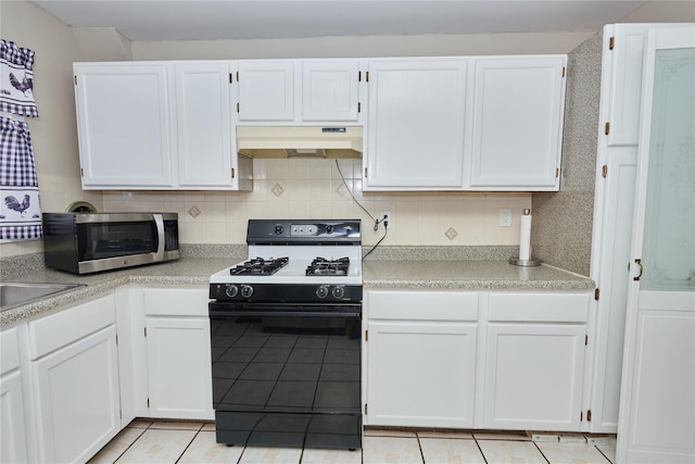 112 N Columbus Ave, Mount Vernon, NY 10553 - kitchen featuring range with gas cooktop, under cabinet range hood, stainless steel microwave, light tile patterned flooring, and white cabinetry
