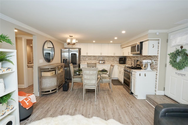 112 N Columbus Ave, Mount Vernon, NY 10553 - kitchen featuring appliances with stainless steel finishes, light countertops, light wood-style floors, white cabinetry, and ornamental molding