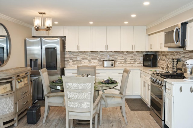 112 N Columbus Ave, Mount Vernon, NY 10553 - kitchen featuring appliances with stainless steel finishes, ornamental molding, white cabinetry, light countertops, and light wood-style flooring