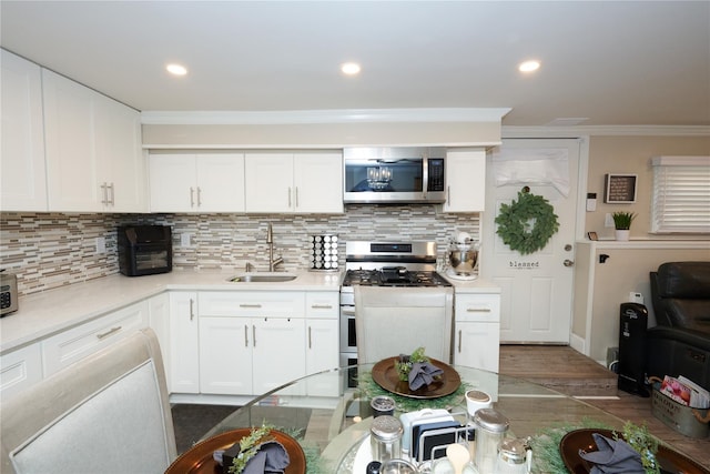 112 N Columbus Ave, Mount Vernon, NY 10553 - kitchen with appliances with stainless steel finishes, dark wood finished floors, white cabinets, backsplash, and ornamental molding