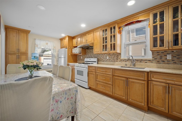 31 Pilgrim St, New Hyde Park, NY 11040 - kitchen with white appliances, under cabinet range hood, backsplash, light tile patterned flooring, and glass insert cabinets