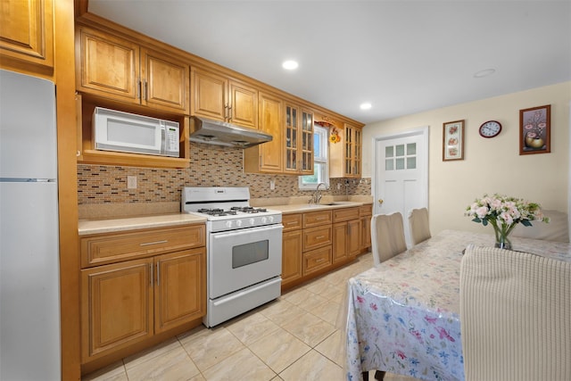 31 Pilgrim St, New Hyde Park, NY 11040 - kitchen featuring white appliances, under cabinet range hood, backsplash, light countertops, and glass insert cabinets