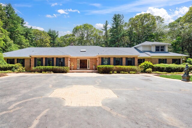 10 Laurel Woods Dr, Upper Brookville, NY 11771 - view of front facade with brick siding, curved driveway, and a chimney