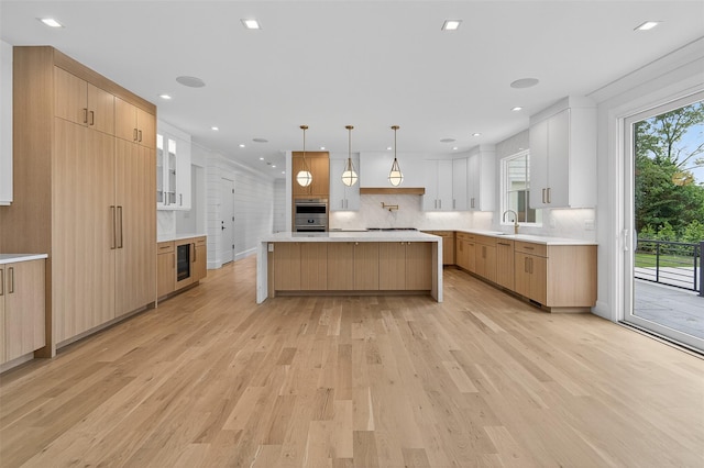 32A Pine Rd, Syosset, NY 11791 - kitchen with light wood-style flooring, backsplash, double oven, light countertops, and a center island