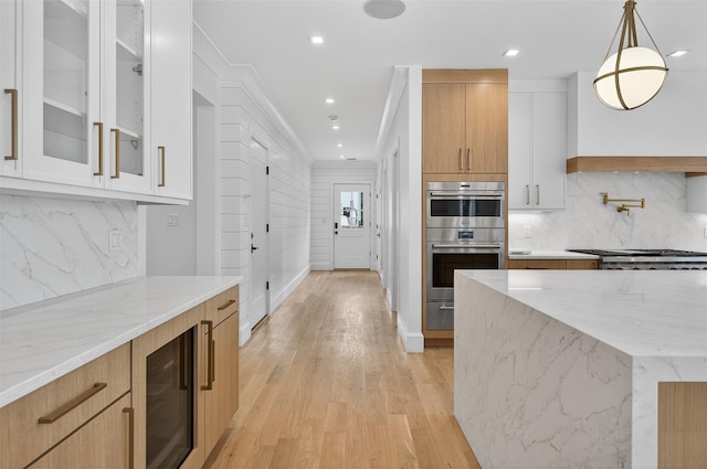 32A Pine Rd, Syosset, NY 11791 - kitchen featuring appliances with stainless steel finishes, wine cooler, light stone countertops, backsplash, and light wood finished floors